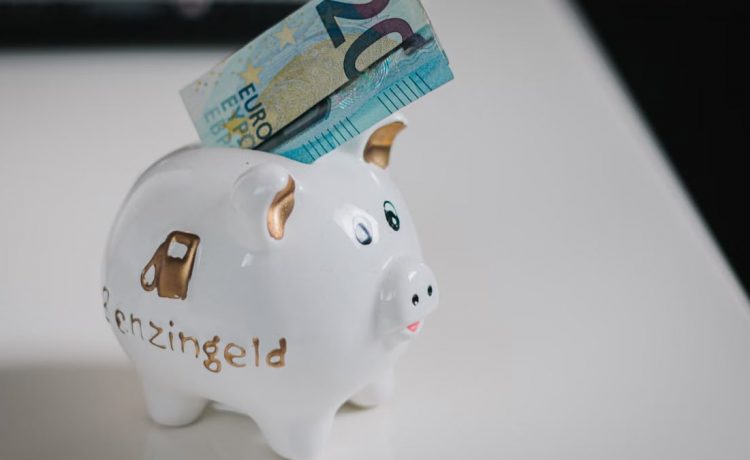 A white piggy bank with a €20 note inserted, symbolizing savings.